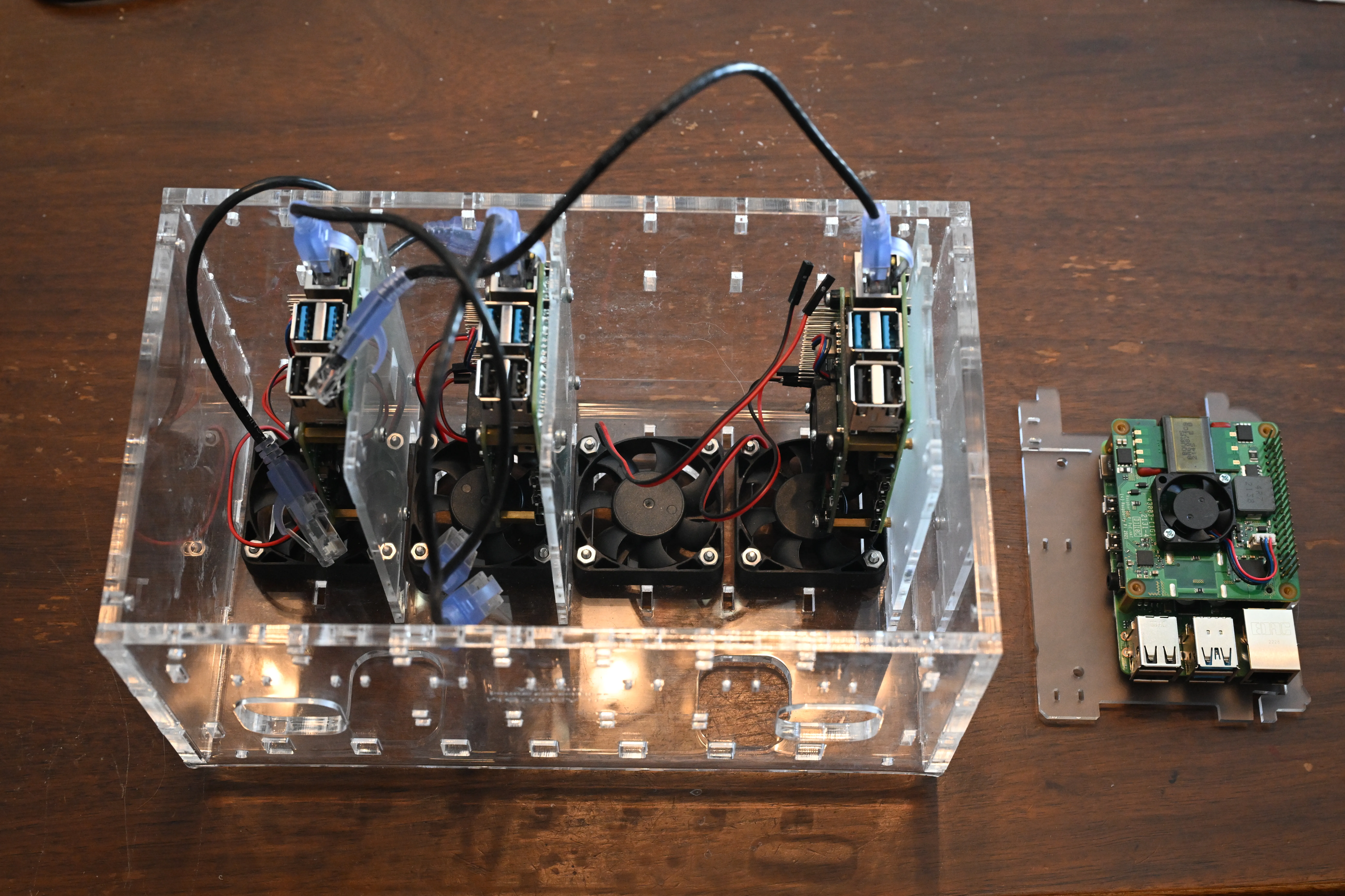 Three of the Pis in place, one ready to get connected to its fan C4Labs Cloudlet CASE with 3 Raspberry Pis installed and plugged into fans, with one Raspberry Pi on its plastic rack ready to be plugged into the fan and installed in the last open place in the CASE